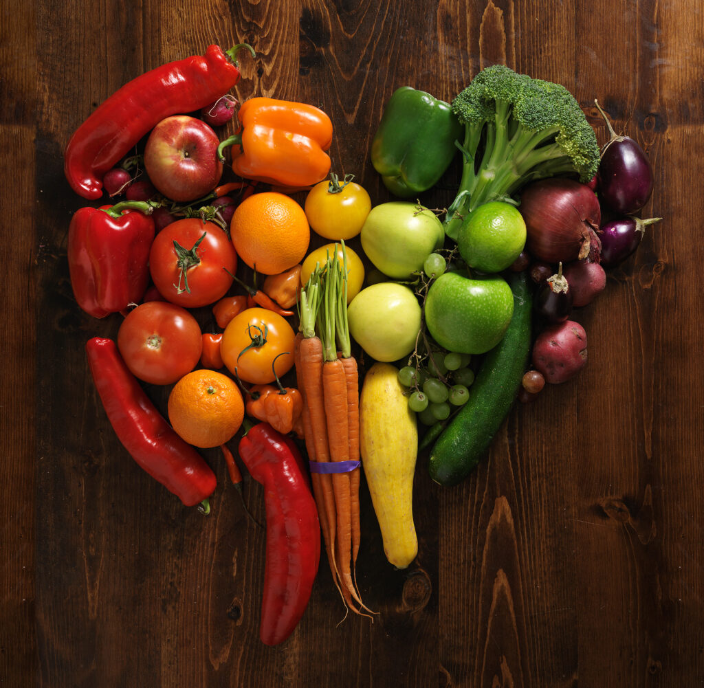 vegetables arranged in a colorful heart shape on a wood background.