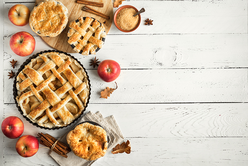 Homemade Apple Pies on white wooden background, top view. Classic autumn Thanksgiving dessert - organic apple pie.